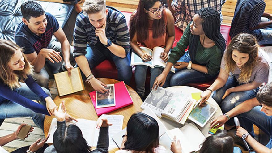 Young people talking around a table with books