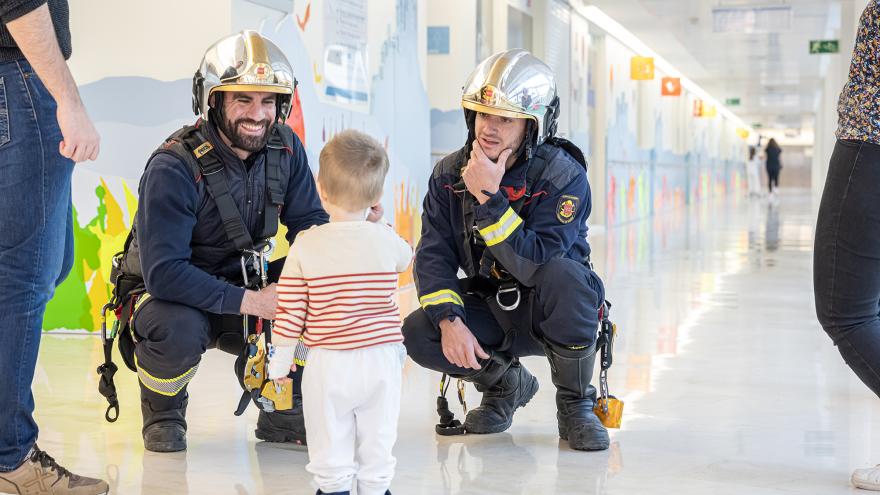 Los bomberos saludan a un pequeño ingresado en el Hospital Gregorio Marañón