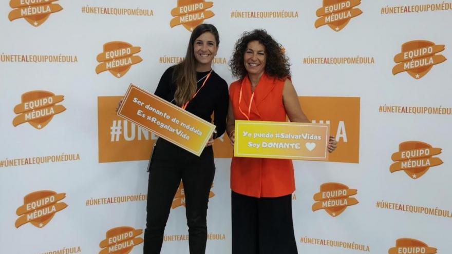 Dos mujeres posando delante de una trasera con logos