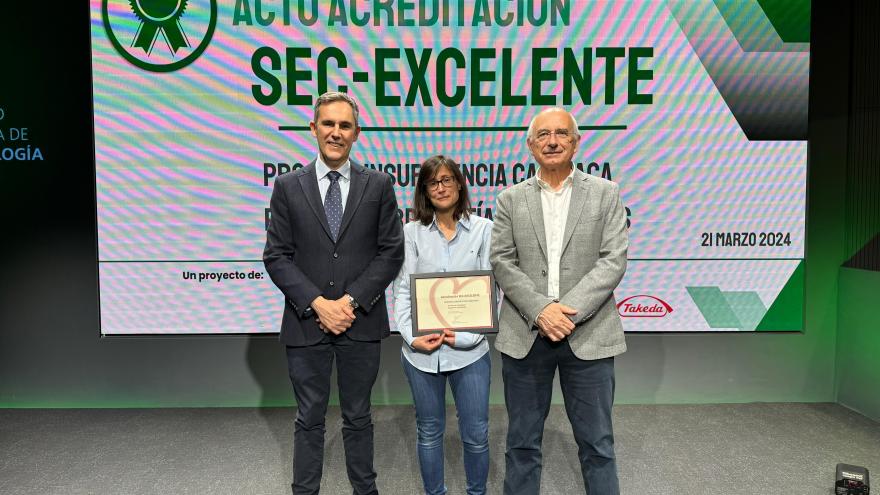 Dos hombre y una mujer están mostrando un diploma en una entrega de premios