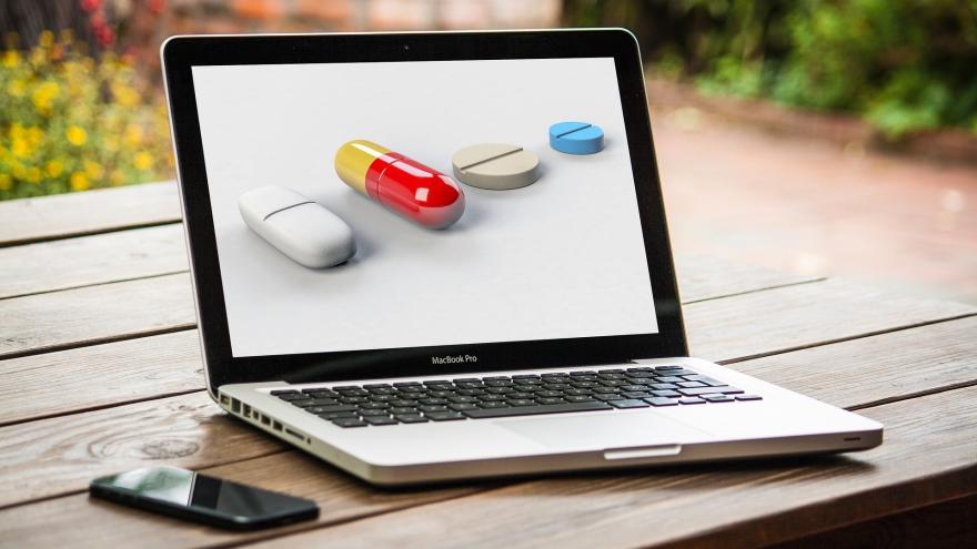 ordenador portátil abierto y con pastillas de medicamentos en la pantalla