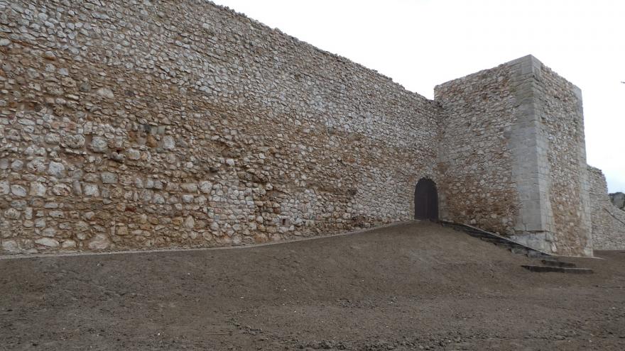 muralla de piedra con torre rectangular y puerta de acceso