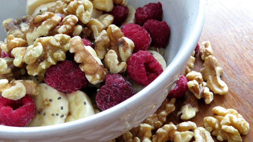 Cuenco con nueces frambuesas y un plátano 