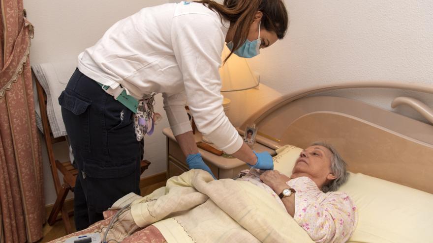 Personal sanitario atendiendo a persona mayor en su cama