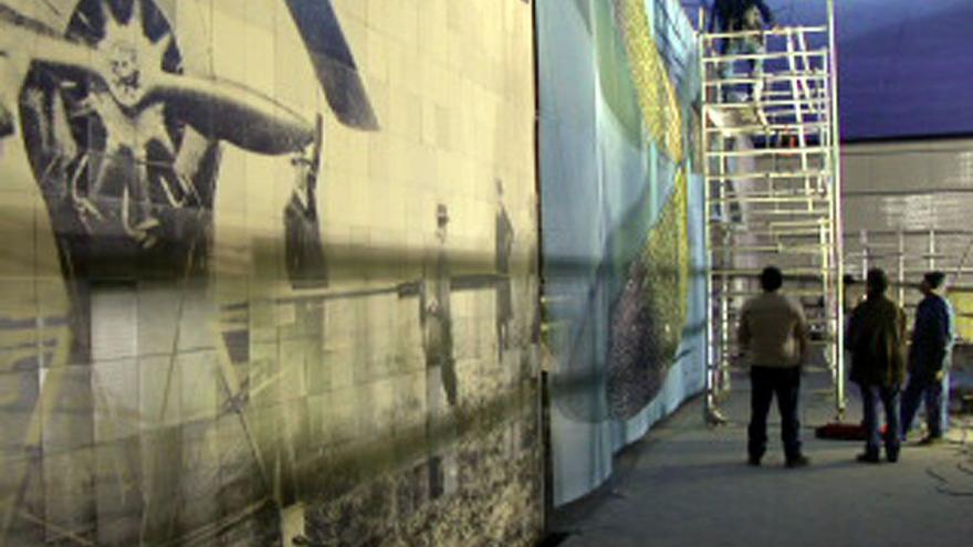 Personal subidos a un andamio colocando el mural