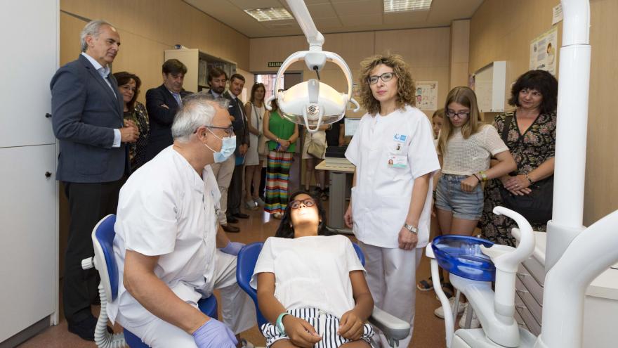 Niña sentada en el sillón de un odontólogo, con una higiniesta dental