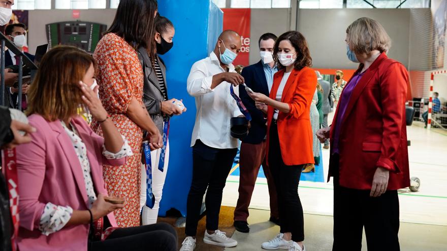 La presidenta hablando con uno de los deportistas que sujeta una medalla en la mano
