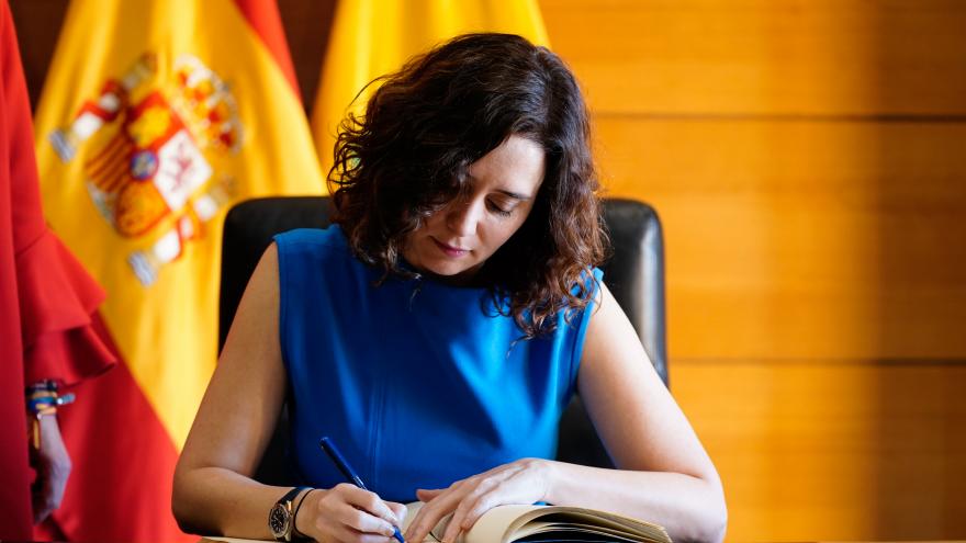 La presidenta, vestida de azul, y firmando un libro durante el Consejo de Gobierno