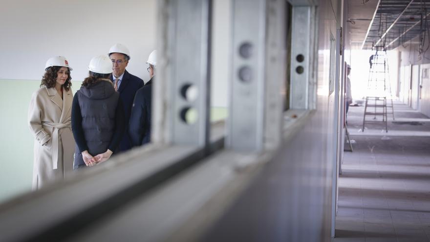 La presidenta con un casco mirando a través de una ventana