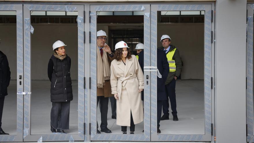 La presidenta con un casco mirando a través de una ventana