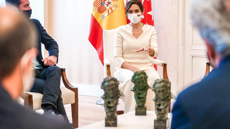 La presidente sentada a una mesa donde hay varios galardones