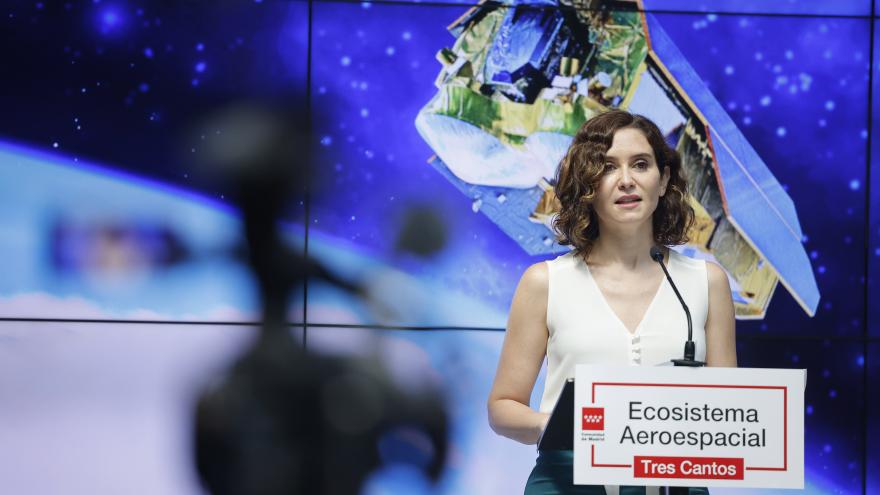 La presidenta  en el atril durante su intervención y con una pantalla detrás
