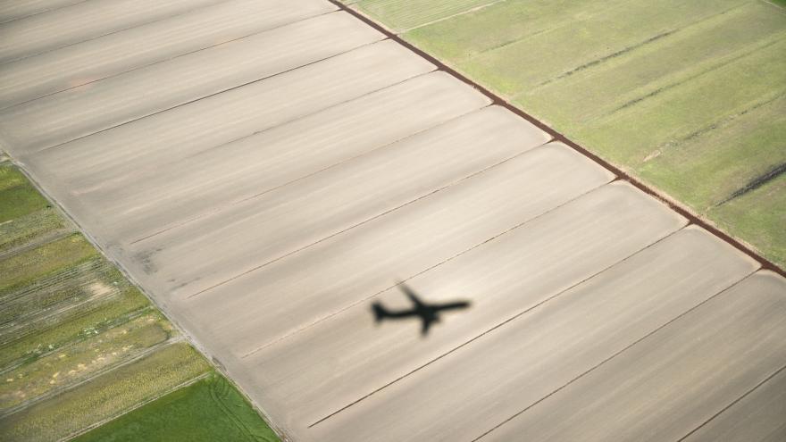 Sombra de un avión sobrevolando un campo