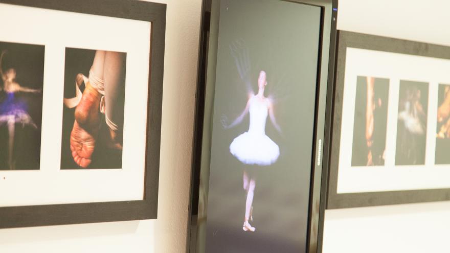 Fotografías y audiovisual de bailarines y bailarinas de ballet clásico, dispuestas en fila en una pared