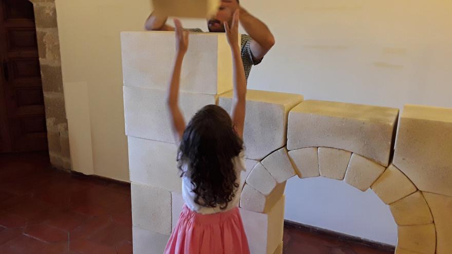 Niña jugando con bloques creando un arco y una torre arquitectónica
