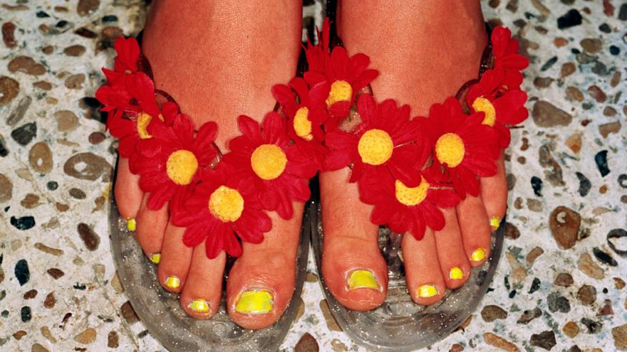 Pies femeninos con chanclas decoradas con flores