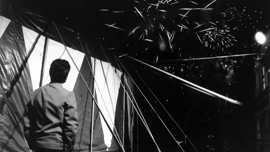 José Muñoz. Circo Mundial, Bilbao, 1992 Colección Museo CA2M ©VEGAP. Madrid, 2025 Hombre contemplando una carpa de circo bajo un cielo cubierto de fuegos artificales