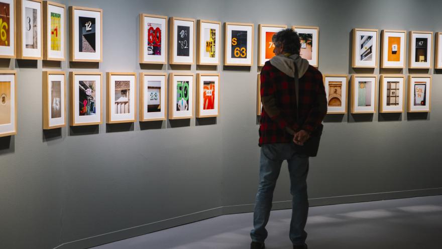 Hombre mirando una serie de fotografías con números en la Sala Canal