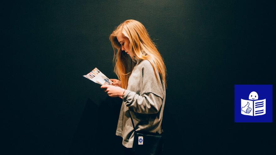 Mujer joven de perfil leyendo un folleto 