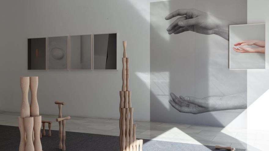 Fotografías de manos colgadas en una pared y juego infantil en madera sobre el suelo