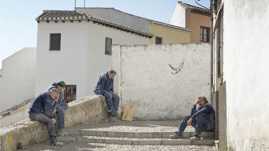 Hombres mayeres sentados en unas escaleras de un pueblo