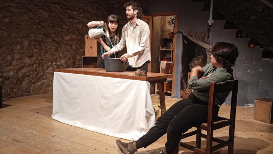 fotografía de escena tres personas delante de  una mesa en una casa de pueblo