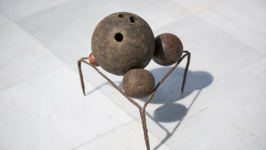 Escultura formada por tres bolas sobre un trébede de hierro