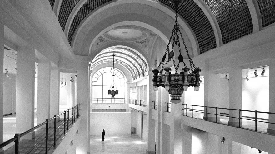 Vista en blanco y negro de la bóveda de cristal, lámpara y sala de exposiciones de la Consejería de Cultura