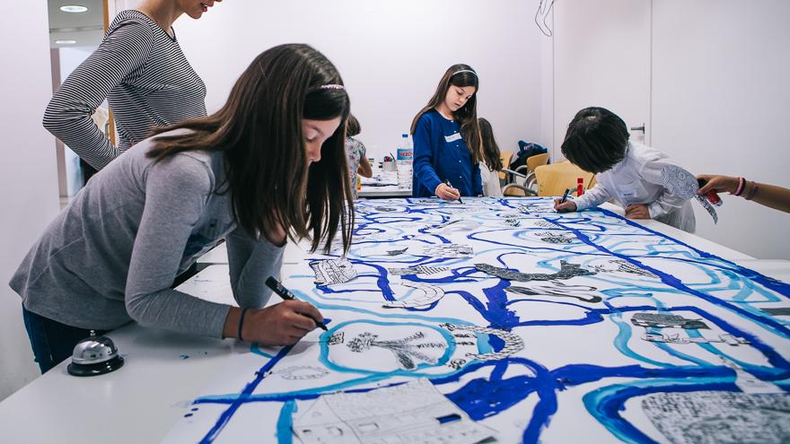 Niños pintando con pinceles líneas curvas en distintos tonos de azul