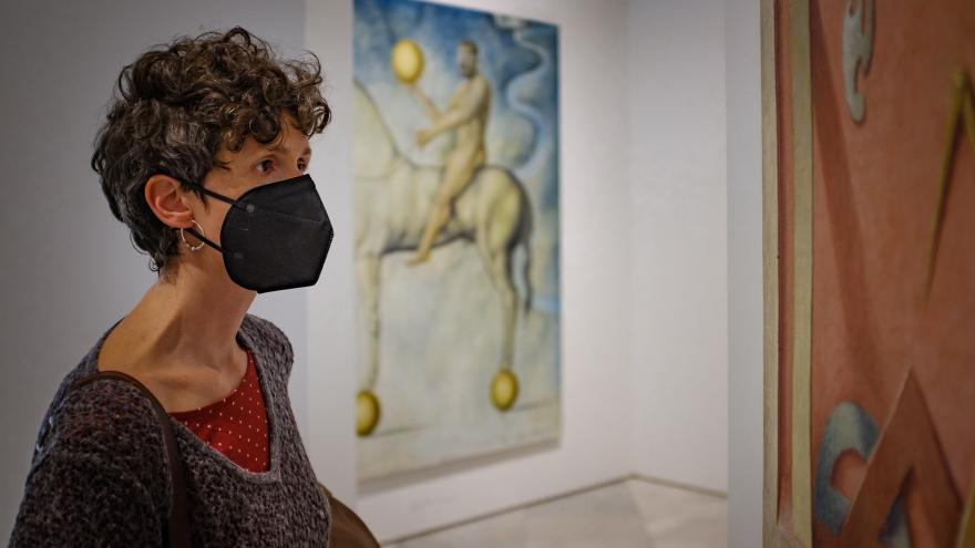 Mujer con mascarilla frente a un cuadro