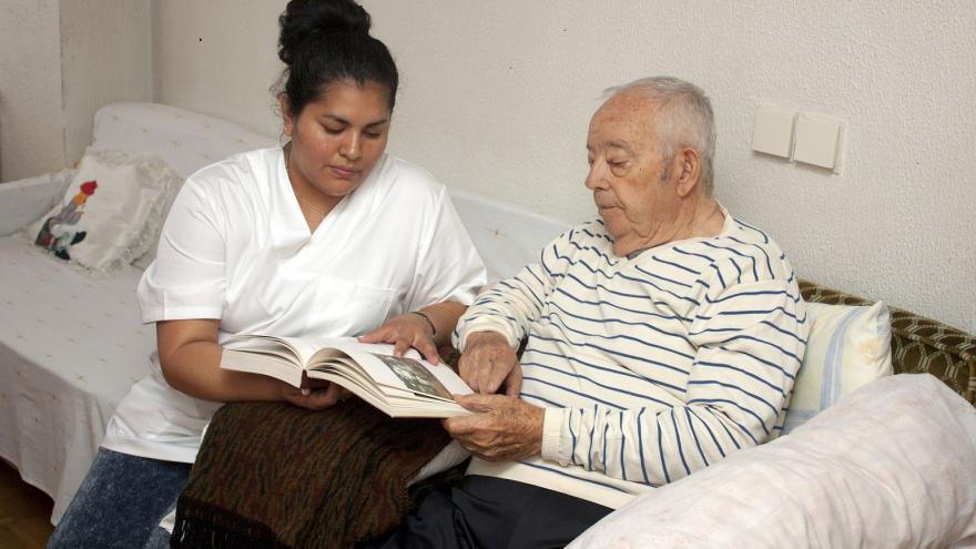 Hombre mayor y cuidadora sentados