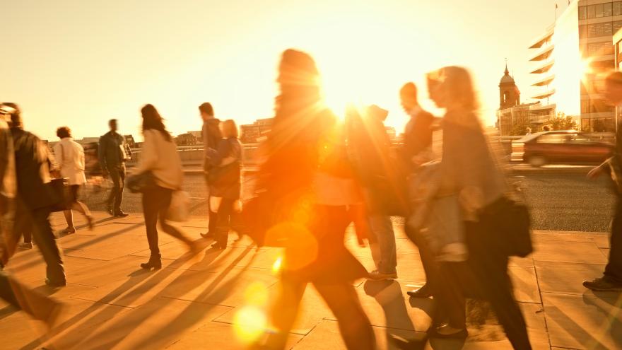 Personas andando con el sol de fondo