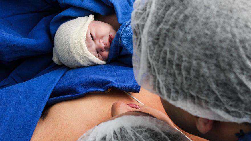 Pareja en paritorio con bebe recién nacido en el regazo