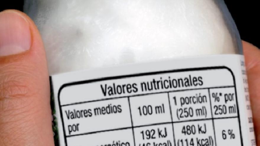 Manos con un yoghurt etiquetado con la información nutricional