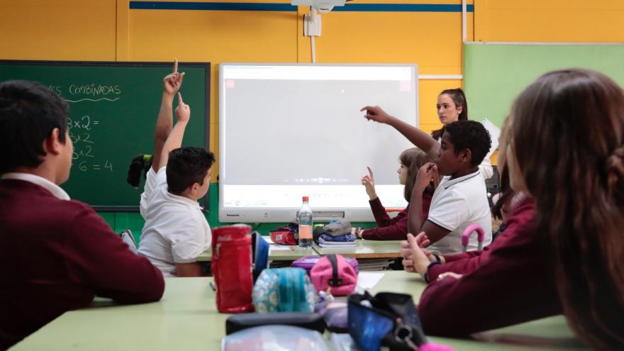 Unos niños levantan la mano en un aula de clase