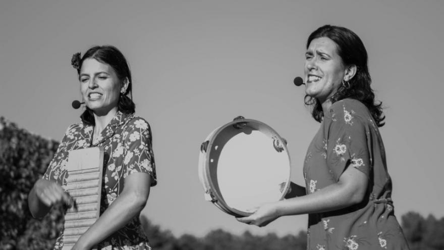 Dos  mujeres cantando en el campo con panderetas 
