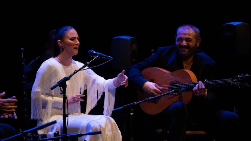 imagen de Lucía Beltrán con vestido blanco cantando, a su lado Patrocinio hijo tocando la guitarra
