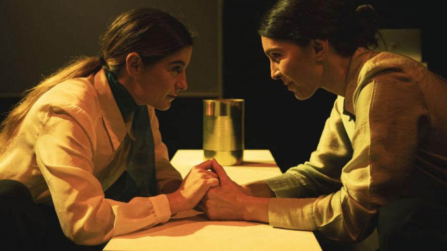 imagen que muestra dos mujeres tomándose de la mano pro encima de una mesa