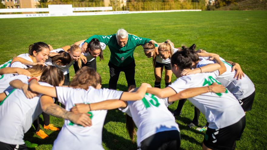 Equipo de fútbol femenino haciendo corro con su entrenador