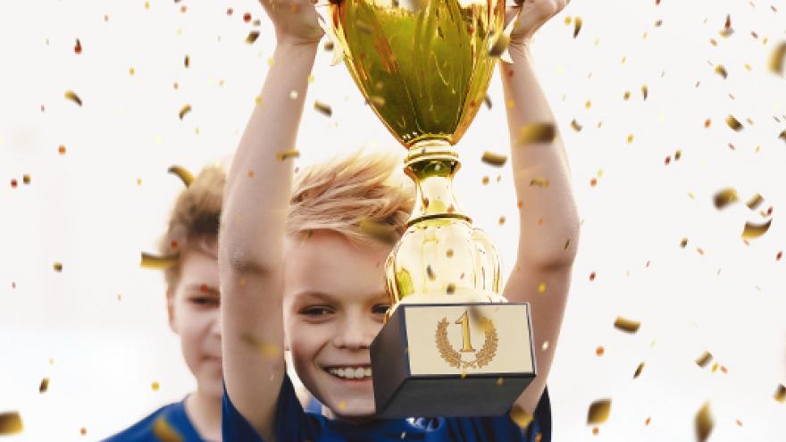 Niños contentos levantando trofeo