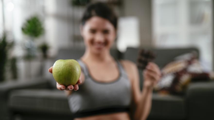 Mujer de fitness eligiendo comer sano o chocolate