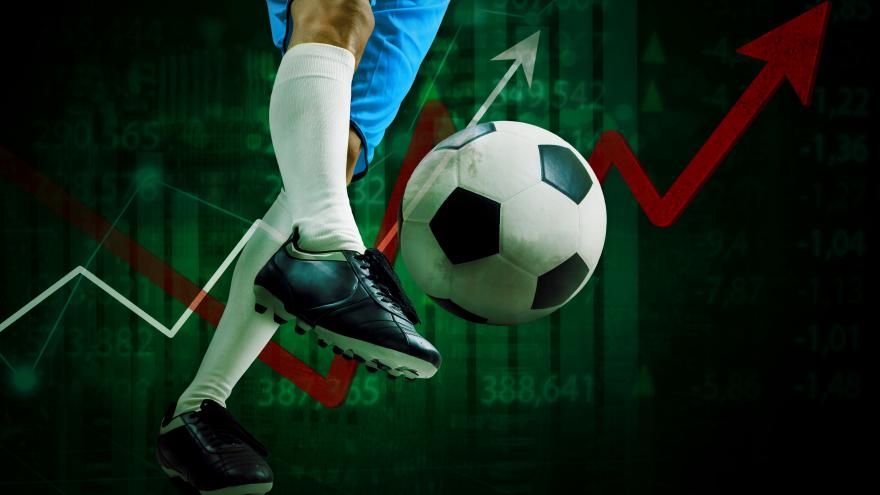 Pierna golpeando un balón de fútbol sobre fondo de gráficos de datos