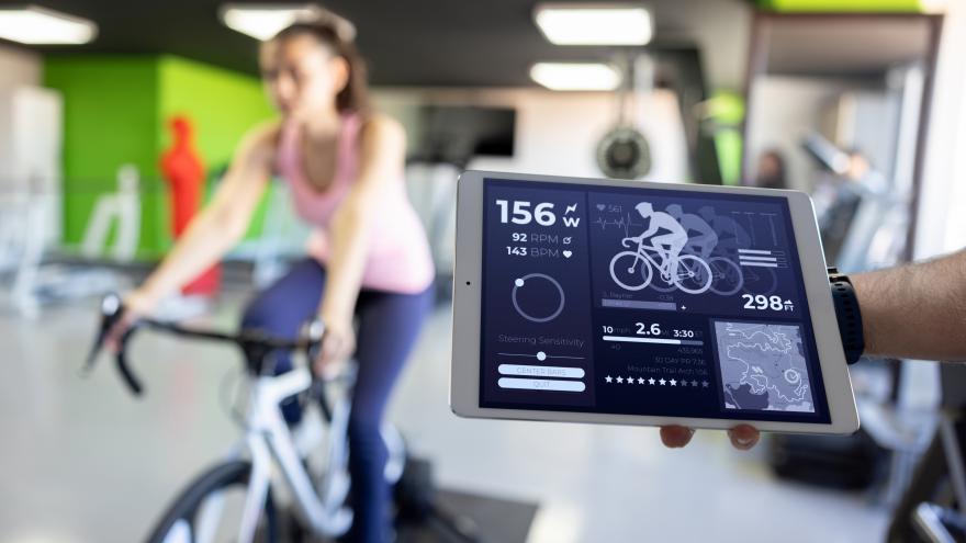 Mujer en forma haciendo una prueba de esfuerzo mientras monta en bicicleta en un gimnasio