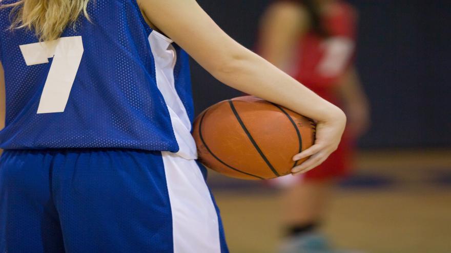 Jugadora de baloncesto sujetando la pelota en la cadera