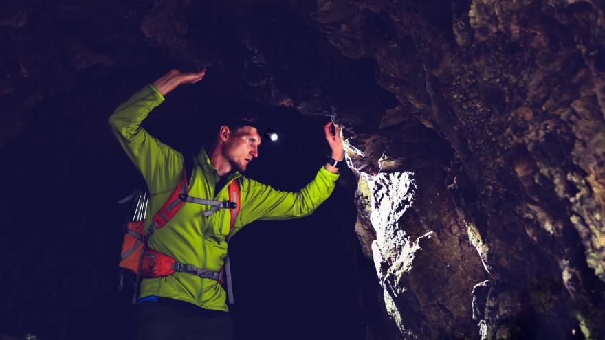 Espeleólogo iluminando una pared de una cueva