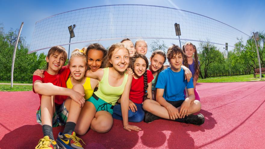 Niños sonrientes sentados en una cancha de voleibol