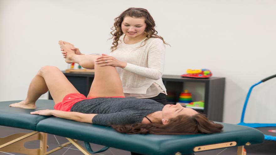 Fisioterapeuta practicando la rodilla de una mujer