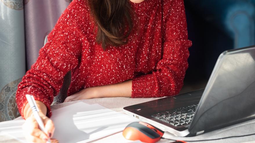 Mujer con un ordenador delante el móvil y muchos papeles en los que está escribiendo
