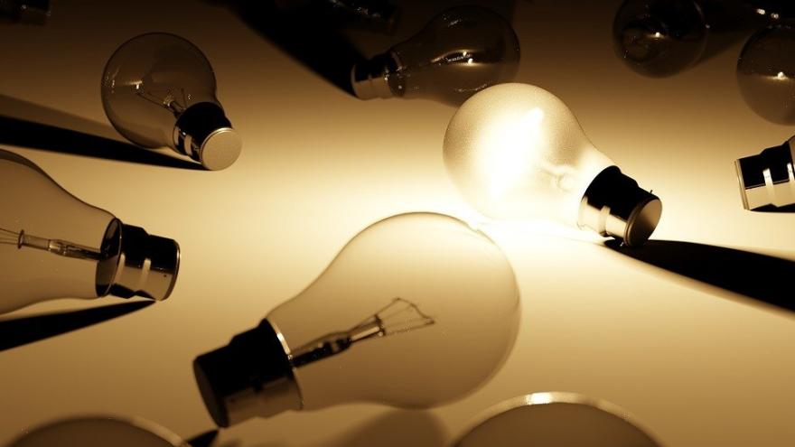 Light bulbs on a dark background, with only one lit