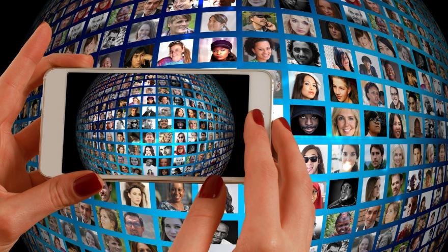 Teléfono movil haciendo una foto a un panel de videoconferencia donde aparecen muchas personas